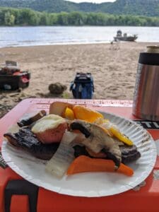 Can you eat bass? prepared bass meal sitting on top of closed orange cooler with body of water in background